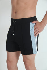 A model wearing black fleece shorts with a grey side panel and a drawstring waistband.