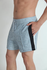 A man wearing grey fleece shorts with a black and white side panel and a drawstring waist.