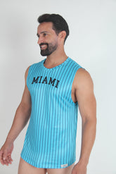 A smiling man wearing a turquoise and navy pinstripe muscle tank top with MIAMI printed on the chest.