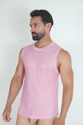 A bearded man wearing a pink lace muscle tank top with a geometric open-work pattern.
