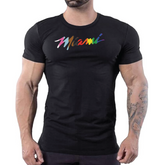 Man wearing a black t-shirt with a colorful Miami Pride brushstroke graphic across the chest.
