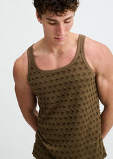 A man wearing an olive green ST33LE Stretch Ripped Knit Tank top with a textured, perforated pattern.