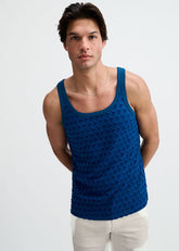 A male model wearing a petrol blue stretch ripped knit tank top against a white background.