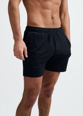 A man wearing black ST33LE textured mesh gym shorts with an elastic waistband against a plain white background.