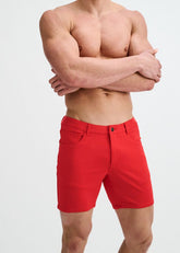 Shirtless male model wearing vibrant cayenne red ST33LE stretch knit shorts against a plain white background.