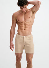 A shirtless man models ST33LE stretch knit crust-colored shorts against a white background, hand behind head.