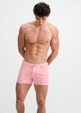 A shirtless male model wearing ST33LE 3-inch stretch knit shorts in petal pink, posing against a white background.