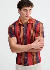 A man models the ST33LE Arrow Stripe Open Knit Short Sleeve Button Down in Navy and Red against a plain background.