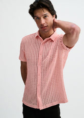 A man poses in a pink short-sleeve open-knit button-down shirt with a rib collar.