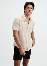 Model wearing vanilla white short-sleeve button-down shirt with eyelet pattern and black shorts against white background.
