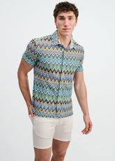 A man modeling a short-sleeve button-down shirt with a multicolored cobalt and sky blue chevron knit pattern.