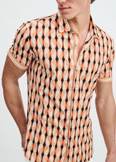 Man wearing a short-sleeve button-down shirt in spice and sand with an abstract geometric pattern.