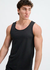 A male model wearing a black ST33LE textured stretch mesh performance tank top against a white background.