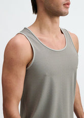 A man wears a grey and black textured stretch mesh performance tank top with a scoop neckline.