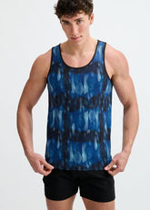 A male model wearing a blue and navy abstract print stretch mesh performance tank top and black shorts.
