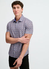 A man models a short-sleeve button-down shirt with a blue and pink diamond print on a white background.