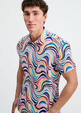 A male model wearing a ST33LE short-sleeve button-down shirt featuring a colorful teal and multi-colored swirl pattern.