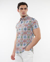 A man wearing a fauna print stretch knit short-sleeved shirt with colorful geometric floral pattern on light background