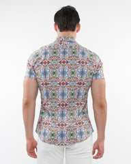 A man wearing a fauna print stretch knit short-sleeved shirt with colorful geometric and floral patterns on light background