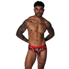 Men's low-rise swim brief in camo print with red waistband, cutouts, and a front drawstring tie.