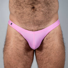 Pink tulio swim thong made of smooth stretchy fabric with a small black brand tag on the waistband back side view