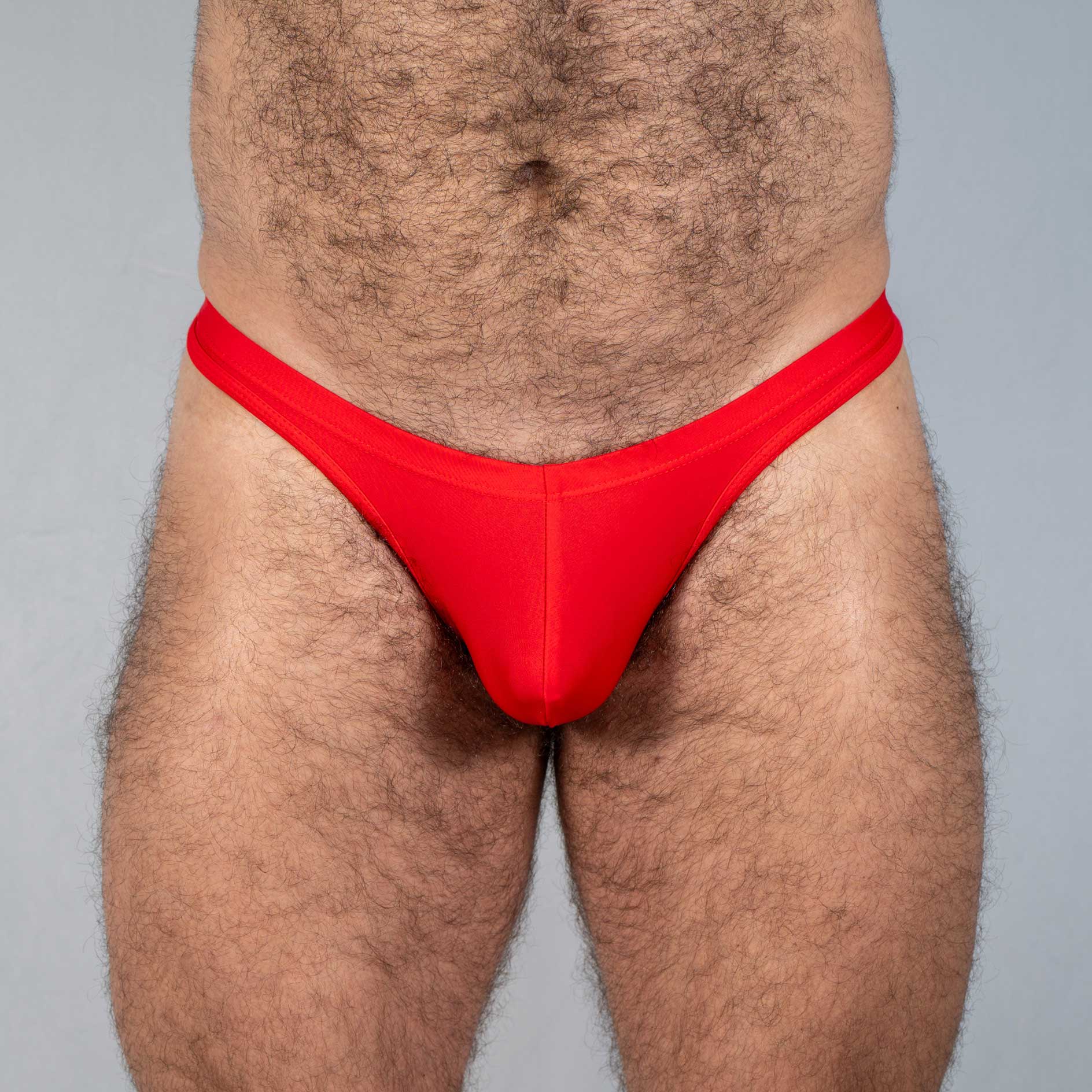 Bright red tulio swim thong made of smooth stretchy fabric in a form-fitting solid design shown from the back side
