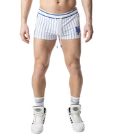A model wearing Nasty Pig white and quartz blue striped trunk shorts with a drawstring and NP logo.