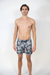 Men’s dark gray Hawaiian print swim shorts with white tropical leaf pattern and black drawstring waistband