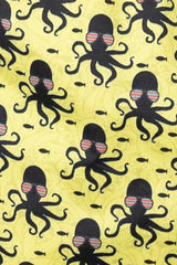 Yellow octopus print swim short fabric with repeating black octopuses wearing striped sunglasses and small fish pattern