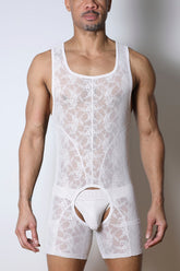 A man wears a white Timoteo Windsor singlet chaps made of sheer floral lace with an open-crotch design.
