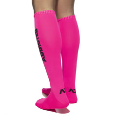Bright pink knee-high ADDICTED neon socks with black branding and logo on the side for stylish casual wear