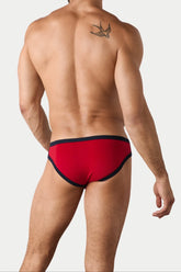 A man with a swallow tattoo wearing red briefs with dark trim, viewed from the back.