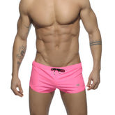 Basic mini short bright pink swim trunks with black drawstring and small logo on the lower right leg