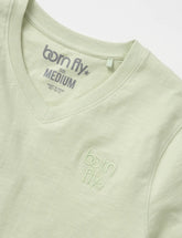 A light green cotton v neck born fly tee with subtle embroidered logo on the chest and matching collar tag