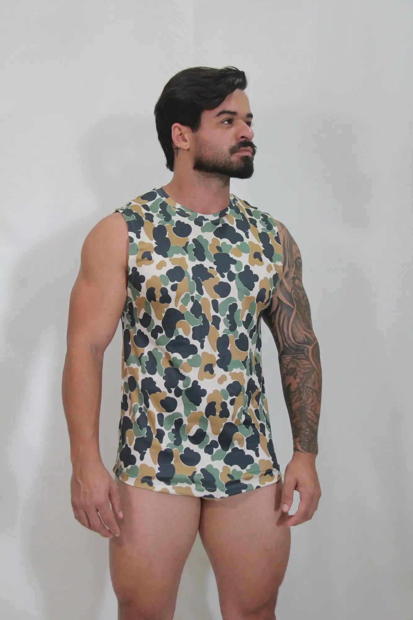 A men’s sleeveless camouflage open arm tank top in green brown and black on white for casual wear