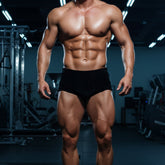 A muscular man wearing black velvet metroMalewear classic bodybuilding trunks 6 inch for posing wear