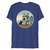Blue heathered t-shirt with a circular graphic of two muscular men with luggage on a dock in front of a cruise ship