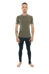 A man wearing a fitted olive green designer raglan crew neck tee with short sleeves paired with black leggings