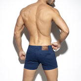 Rear view of a shirtless man wearing ES Collection plain blue cargo shorts against a white background.