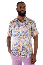 A man wearing an exclusive buzz s/s shirt with a blue orange and cream paisley pattern on a light background