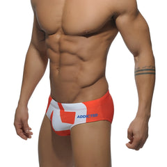 Extra-large logo brief swim trunks in orange and white with bold geometric design and addicted brand name in blue