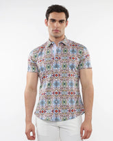 A man wearing a fauna print stretch knit short-sleeved shirt with colorful geometric patterns in blue green red and beige