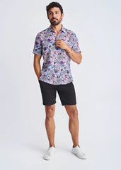 A man wearing a floral lightweight linen tencel short-sleeved shirt in shades of purple blue and pink