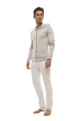 A man wearing a heather gray form-fit crossover yoga track performance hoodie with matching white pants