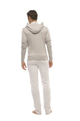 A man wearing a heather gray form-fit crossover yoga track performance hoodie with ribbed cuffs and waistband