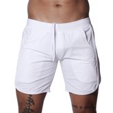 White athletic shorts featuring an elastic waistband with drawstring, side pockets, and curved hem detail.