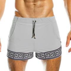 Light gray gigo arabesque swim trunks with bold black greek key hem and matching drawstring with metallic aglets
