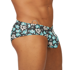 Black gigo comics swimbrief swim trunks with teal and white cartoon monsters and a metallic ring waistband accent