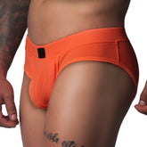Bright orange textured mesh athletic brief with a wide waistband and a small black rectangular logo patch in front.