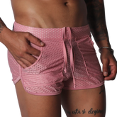 Pink, mesh athletic shorts with a drawstring waistband, side pockets, and curved hem detail.